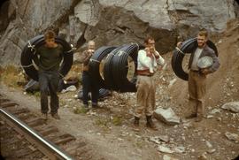 Carrying rolls of rubber water pipe along CN line.  left to right: R. Cox, P. Holburn, D. Sanger,...